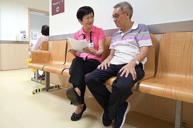 Volunteer Molly Lim gives advice to Mr Cheong Chue Wan, a patient at TTSH Eye Clinic.