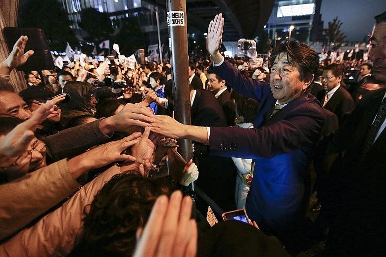 Japanese Premier Shinzo Abe greeting voters on the final day of the campaign outside the Akihabara rail station in Tokyo yesterday. A two-thirds "supermajority" in the Lower House will help pave the way for Mr Abe to realise his grandiose ambition of