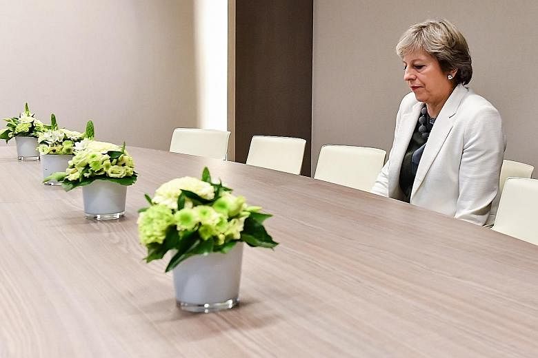 Social media on Friday mocked embattled British Prime Minister Theresa May over a photograph of her sitting alone in a room awaiting EU Brexit talks, calling it a "metaphor" for her isolated position. In the viral snap, May is seen alone at a large t