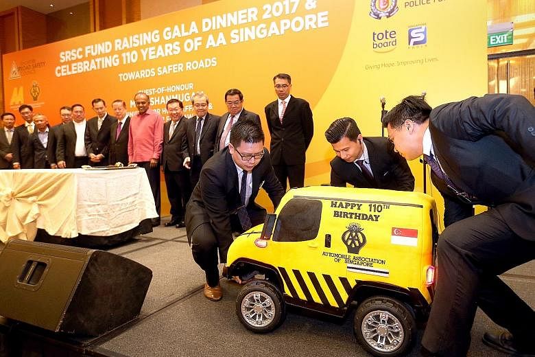 The 110kg Automobile Association cake being carried on stage at the dinner event yesterday. It was cut by Mr K. Shanmugam (in pink) and members of the SRSC.