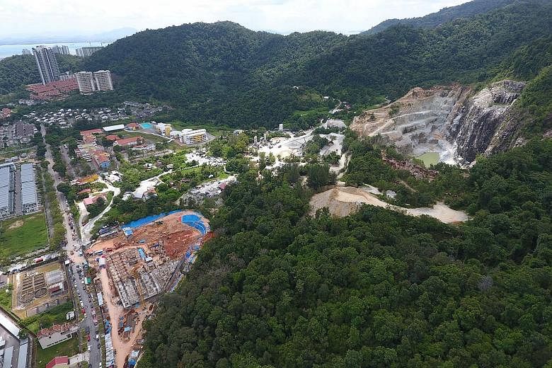 The construction site in Penang where the landslide occurred (left), with a quarry on the right. Malaysia's environment ministry says it had earlier rejected an application by the developer to build on the site because it was next to an active granit