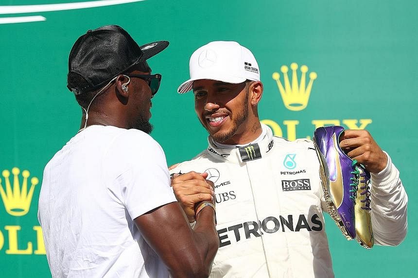 Top: Retired Jamaican sprint legend Usain Bolt in his signature "lightning Bolt" pose before the start of Sunday's US Grand Prix in Austin, Texas. Above: Bolt presenting race winner Lewis Hamilton with a pair of spikes made for his August World Champ