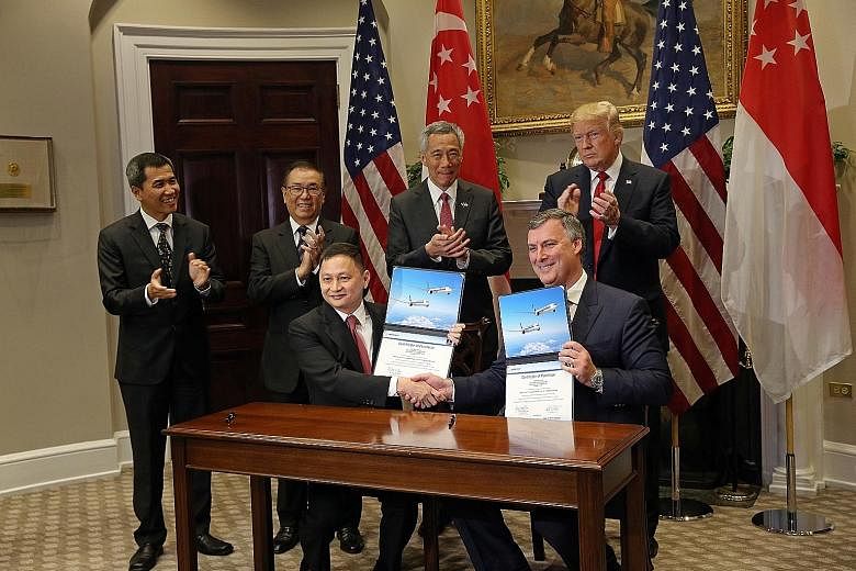 US President Donald Trump, Prime Minister Lee Hsien Loong and (from left) Mr Lau Hwa Peng, SIA senior vice-president, engineering, and SIA chairman Peter Seah witnessed the signing of the agreement between SIA CEO Goh Choon Phong (seated) and Boeing 