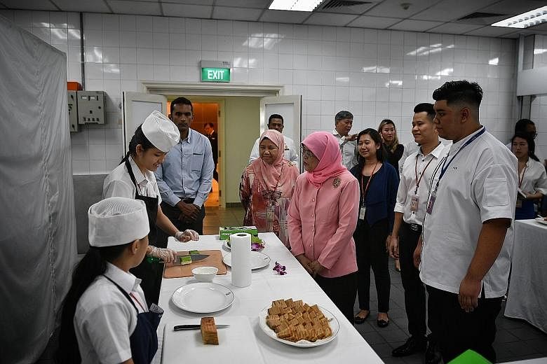 Murial Chua, 16, cutting kueh as she chats with President Halimah Yacob at the Istana kitchen, where the teen has learnt to make cookies and kueh over the past two weeks.