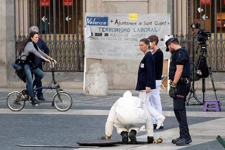 Police inspecting a drain near the Catalan presidency's headquarters in Barcelona yesterday, on the eve of the regional Parliament's plenary session in which the unilateral independence declaration could be passed. Spain has vowed to start taking ove