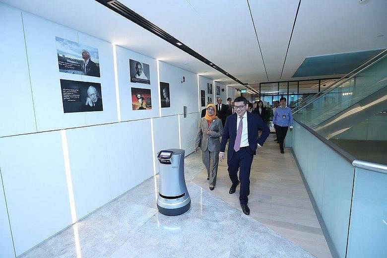 President Halimah Yacob being guided by the "way finder robot" during her visit to GIC's offices on Tuesday, alongside GIC chief executive Lim Chow Kiat. The President was accompanied on her visit by the Council of Presidential Advisers. They were gi