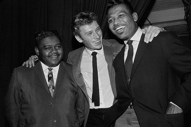 Fats Domino (far left) with French singer Johnny Hallyday (centre) and US boxing champion Ray Sugar Robinson following Domino's performance at the Palais des Sports in Paris on Oct 20, 1962.