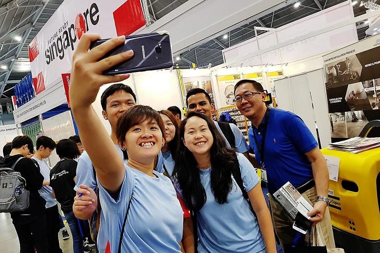 Singapore Polytechnic student Emma Tan Xin Rong (centre, with long hair), 17, posing for a picture with fellow students and senior lecturer Teo Kian Hun at the Singapore Construction Productivity Week trade show.