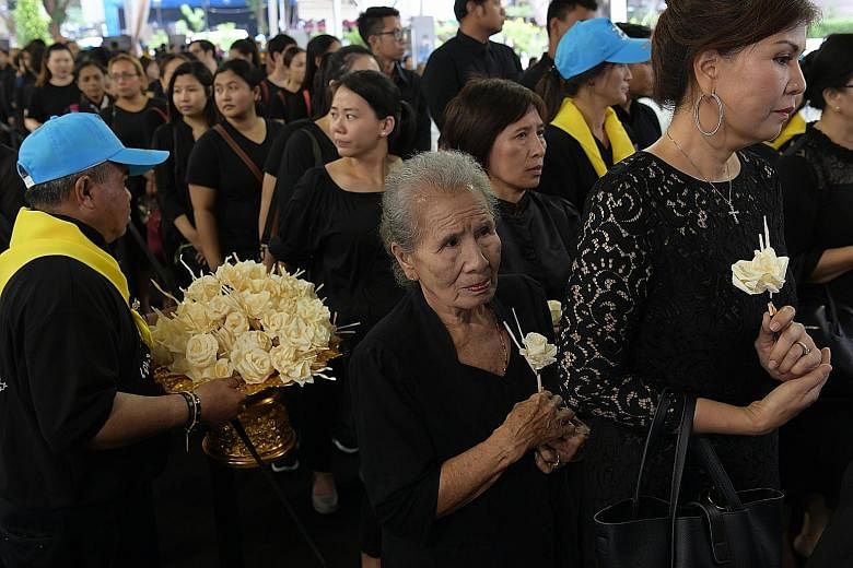 Many of the mourners placed sandalwood flowers in front of the late King's portrait at the Royal Thai Embassy in Orchard Road yesterday. The proceedings in Bangkok were also broadcast live.