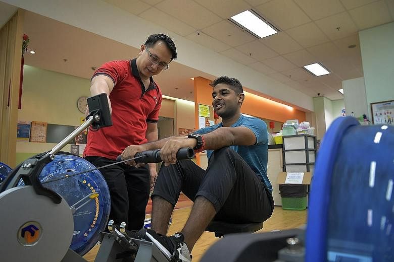 Mr Sathish Panirchelvam using a rowing machine at the wellness centre as principal physiotherapist Tay Hung Yong supervises him.