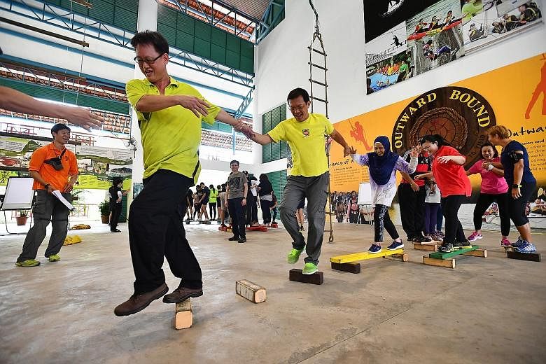 Parents celebrate after completing a task in which everyone has to pass a ball to the next person at the same time without dropping any of the balls. Engineer Derick Choo, 46, and other parents work together, using planks and blocks to move from one 
