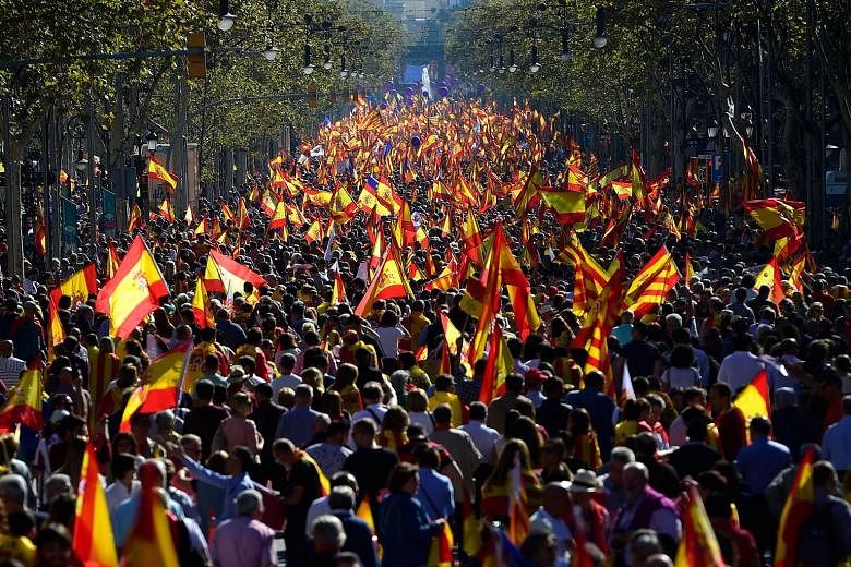 Protesters singing and clapping as they march through Barcelona's streets in sea of red-and-yellow Spanish flags yesterday.