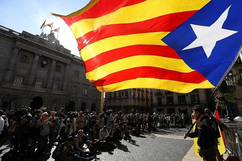 A demonstrator waving a Catalan flag outside the region's Palau de la Generalitat in Barcelona yesterday. The main civic groups behind the pro-independence campaign had called for widespread civil disobedience but most workers started their working d