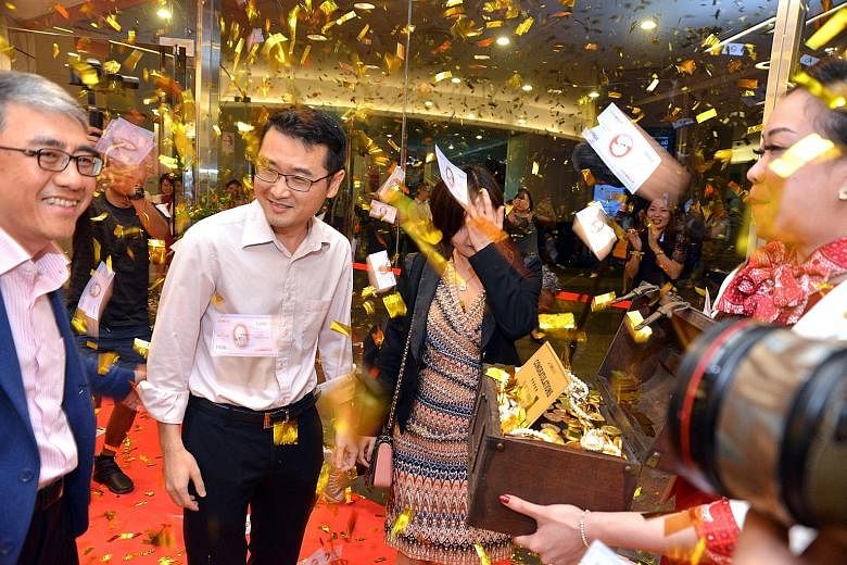 Confetti raining down on Mr Luo Xiang Yue and his wife, Ms Zhong Hua Qiang, at CIMB Bank's Raffles Place branch yesterday. Mr Luo, who won $1 million, said: "I suspected absolutely nothing. I'm still not over the shock. Is this real?"