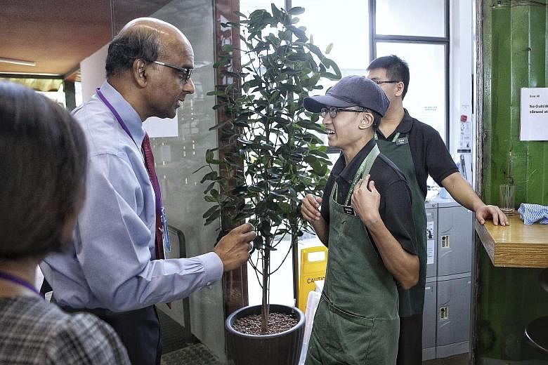 Deputy Prime Minister Tharman Shanmugaratnam with barista Salihin Nakmin, 21, at the Art+Coffee cafe, part of The Art Faculty by Pathlight at the Enabling Village, yesterday. Mr Tharman was attending the launch of a book to mark the 20th anniversary 