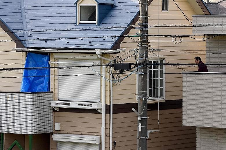 Above: The two-storey apartment (with blue sheet) in Zama city in Kanagawa prefecture, Japan, where the body parts were found. Left: Investigators removing items from the flat yesterday. Home owner Takahiro Shiraishi told police he cut up his victims