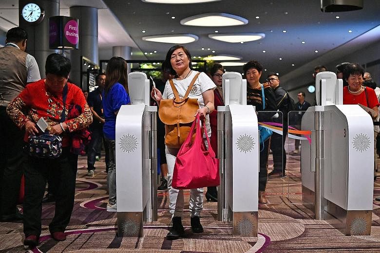 Hong Kong-bound passengers on their way to board Cathay Pacific Flight CX650, the first flight to depart Changi Airport's Terminal 4 yesterday. They were the first to experience the new terminal's automated do-it-yourself processes for check-in, bag 