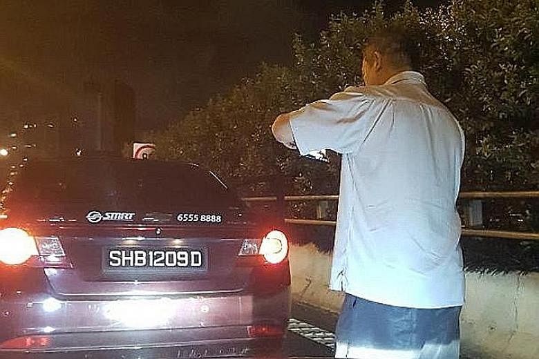 The cabby (above) taking photos of his vehicle during the incident. Mr Chia Hock Herng, the Audi driver accused of rear-ending the taxi, said the cabby got out of his vehicle and appeared to want to help, but later claimed his taxi was hit.