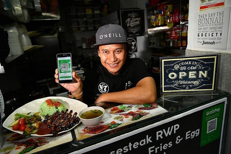 Mr Nornizam Amin, 46, owner of Rayyan's Waroeng Penyet, with his signature ayam penyet dish and the QR code for his stall at Eden Garden Cafe in Telok Ayer Street yesterday, His is one of 25 restaurants and hawker stalls accepting GrabPay.