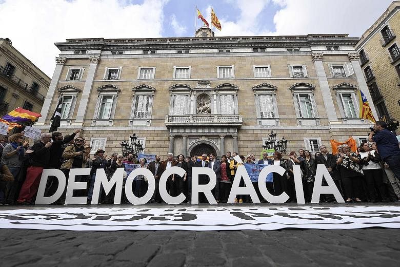 Protesters standing behind a "Democracy" sign in Barcelona yesterday as members of the deposed Catalan government were being questioned in Madrid.