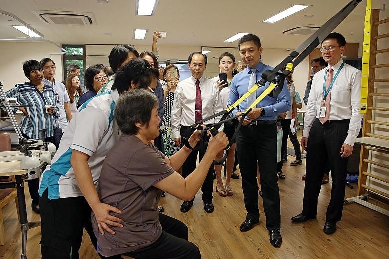 (From right) NTUC Health's residential care head Leon Luai, Speaker of Parliament Tan Chuan-Jin and NTUC Health chief executive Chua Song Khim observing former nursing home resident Ang Cheh Eng doing exercises, at the official opening of NTUC Health