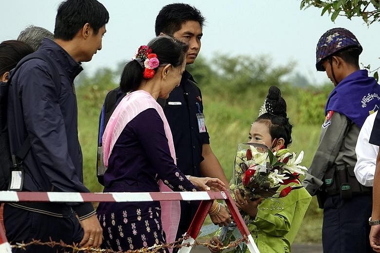 Ms Aung San Suu Kyi receiving flowers from a girl at Sittwe Airport in Rakhine state yesterday. Ms Suu Kyi visited violence-hit Maungdaw and Buthidaung during her one-day trip.