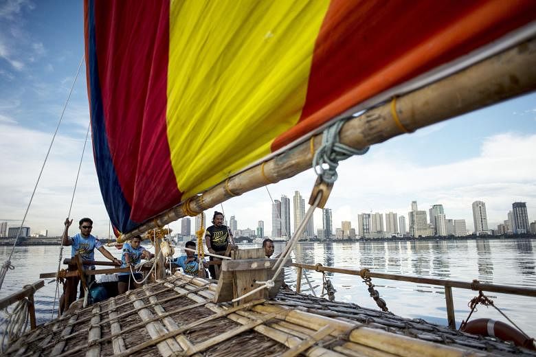 Deckhands aboard a replica of a traditional Philippine wooden boat, known as a balangay, sailing their craft in Manila Bay. The replica of the ancient boat, which dates back as far as AD320, is one of two that will make a six-day journey to southern 