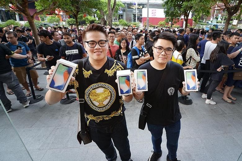 University students Supakorn Rieksiri (far left) and Kittiwat Wang flew in from Thailand to collect yesterday the two iPhones each that they pre-ordered on Oct 27.