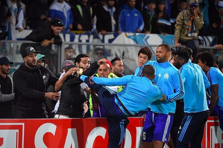 Marseille defender Patrice Evra aiming a kick at a fan before their Europa League tie at Vitoria Guimaraes. Uefa have levelled a violent conduct charge against him, which will be heard next Friday.