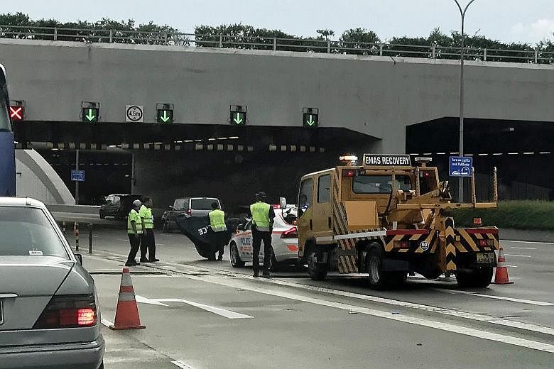 Police officers at the scene of the accident involving two off-duty police officers on the Marina Coastal Expressway yesterday. Eyewitnesses said they saw damaged motorbike helmets and blood.