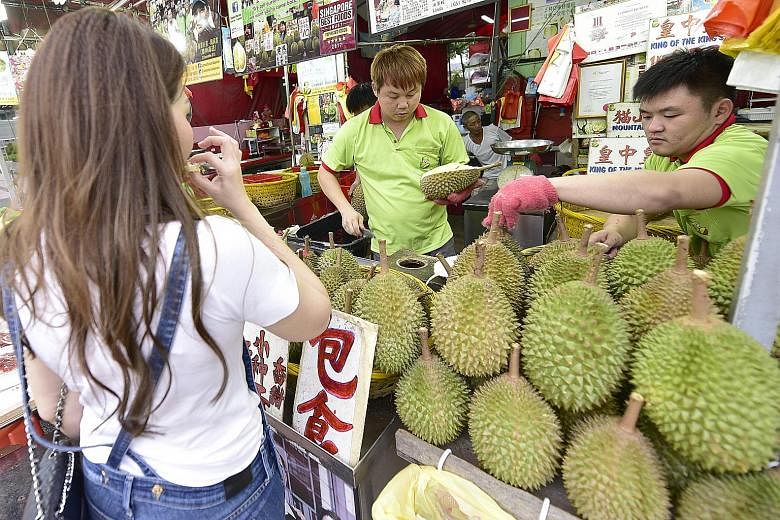 Sellers doing business at Combat Durian in Balestier Road. The vendor saw sales drop by 20 to 30 per cent during the last season in June and July owing to the higher prices, but owner Linda Ang said: "Hopefully, with more supply coming from Pahang an