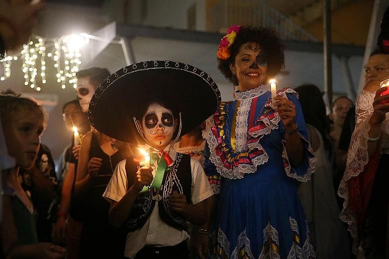 Above: Ms Rocio Sanchez, 43, and her son Nicolas Cornejo, eight, take part in a candlelight procession around the compound. Left: A number of guests, like Ms Cristina Cortes, who is in her 40s, came dressed in traditional Mexican outfits.