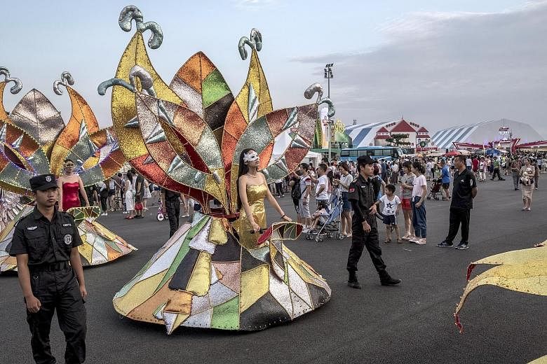 Revellers eat and drink at long tables (right) at the Qingdao International Beer Festival in Qingdao, China, an annual celebration of lager that looks similar to Germany's Oktoberfest. Celebratory events at the festival include a costume parade (abov