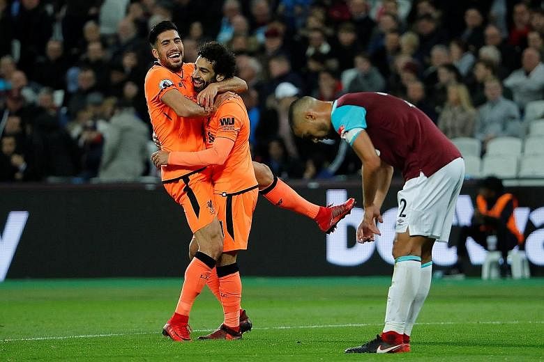 Above: A dejected West Ham manager Slaven Bilic after the hosts were defeated 4-1 by Liverpool. Left: After scoring his side's fourth goal, Liverpool's Mohamed Salah (centre) embraces team-mate Emre Can while the despair is evident in the body langua