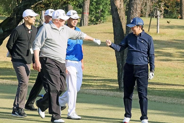 Visiting US President Donald Trump giving Japanese Prime Minister Shinzo Abe a "fist bump" as they played golf, accompanied by World No. 4 golfer Hideki Matsuyama (middle, in blue) at the Kasumigaseki Country Club in Kawagoe yesterday. Mr Abe said he
