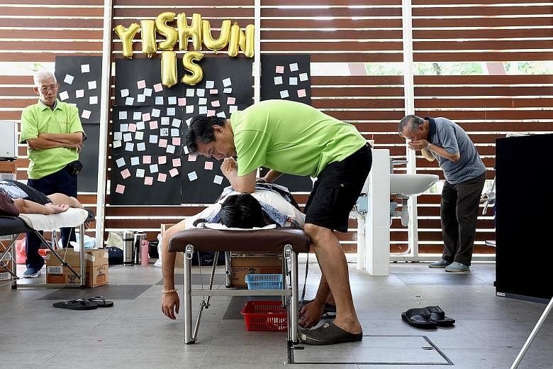 Mr Lim Yow Hoon, 61, giving a massage at Yishun Park Hawker Centre on Sunday as part of a fringe activity for the exhibition, This Is Yishun. Mr Lim, who gives free massages to residents living near his provision shop, is one of several residents fea
