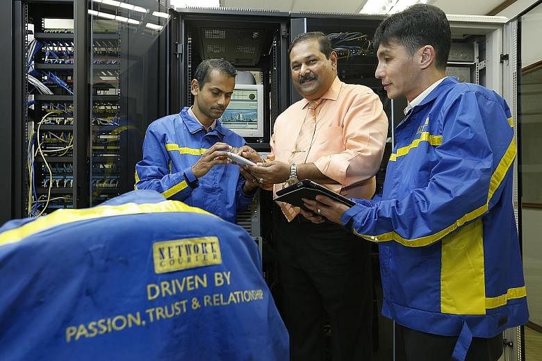 Mr V.S. Kumar (centre) with system administrator Tamil Selvan and operations supervisor Allen Koo in the Electronic Data Processing room, where high-end servers are stored and software such as the Virtual Client system is managed. The system can rout