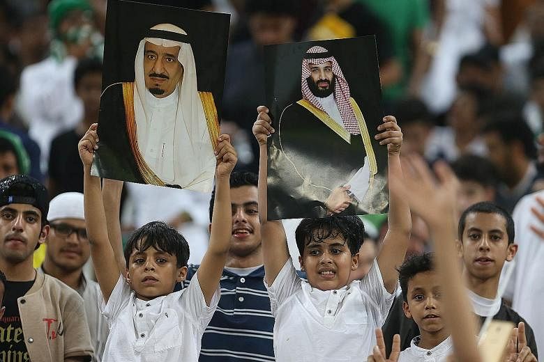 Football fans hold up portraits of King Salman and Prince Mohammed during a Fifa World Cup 2018 qualification match.