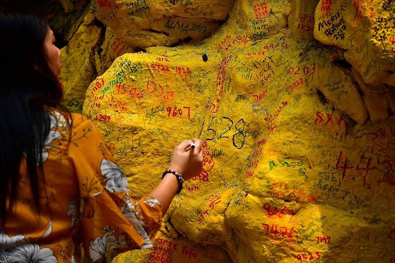 Devotees at the Da Bo Gong temple. Figures from the Singapore Land Authority show that over the past five years, about 42,000 people visited Kusu Island during the pilgrimage season each year. A devotee writing numbers and wishes on the surface of a 