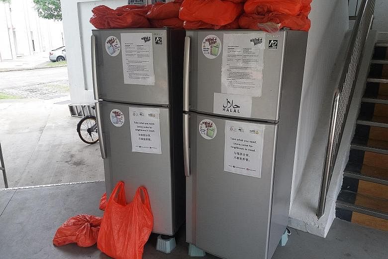 In the Clementi West void deck (above), resident Tan Soon Nan, 78, opens a drawer full of coffee and tea packets. At Block 441, Tampines Street 43 (right), two refrigerators are placed in the lift lobby and residents can stock them with food for need