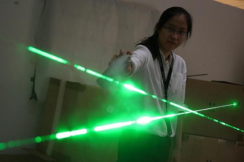 Above: Team officer-in-charge Lim Li Shi using a spray to trace laser beams that outline the trajectory of bullets. Left: A forensic light source being used to detect traces of evidence such as fingerprints.