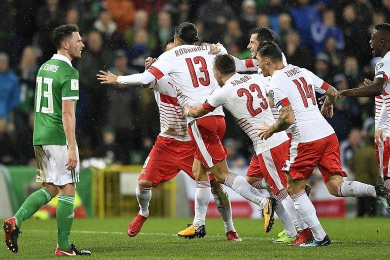 Switzerland players celebrating after Ricardo Rodriguez scored the crucial penalty in the 1-0 win, as Northern Ireland midfielder Corry Evans watches on. The return leg of the World Cup play-off will be played tomorrow.