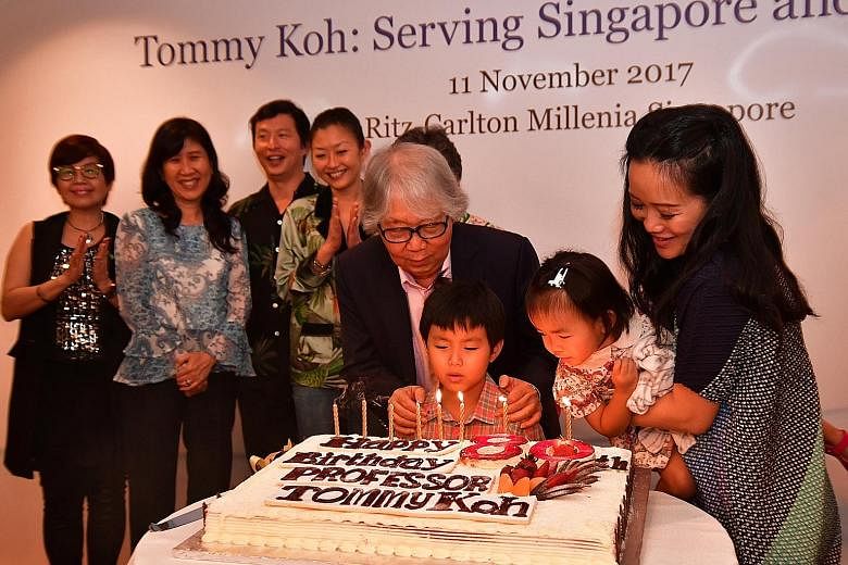 Professor Tommy Koh blowing the candles with his grandchildren Toby Koh and Tara Koh, and daughter-in-law Tan Su-lyn. In the background are his son Wei Koh (third from left) and other members of his family.