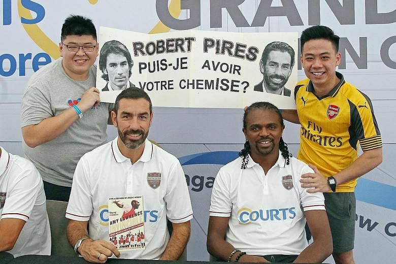 Josiah Tan (left) and Zheng Xuan, hold up a sign askingRobert Pires (third from right) for his shirt at the Courts Megastore yesterday
