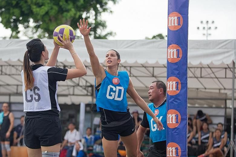 New Zealand Silver Ferns' Kayla Cullen defending a shot by Singapore goal shooter Yu Meiling, as M1 chief innovation officer Alex Tan awaits a rebound, during a charity exhibition game at the M1 Corporate Netball Challenge. Yesterday's event saw 35 t