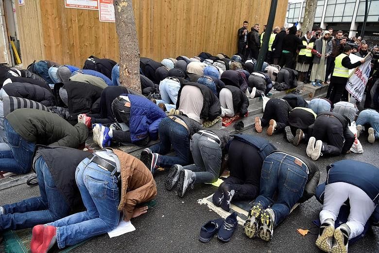 Muslims praying in a street in Clichy, near Paris, last Friday, while city mayor Remi Muzeau and other political leaders protest against the public worship. Lawmakers are calling for a ban on what they see as an unacceptable use of public space, whil