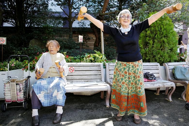 Elderly Japanese citizens working out with wooden dumb-bells during a health promotion event in Tokyo in September.