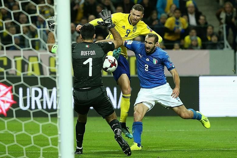 Sweden forward Marcus Berg challenging Italian defender Giorgio Chiellini for the ball as Italy goalkeeper Gianluigi Buffon looks to thwart his advances. The Italians have to overturn a one-goal deficit to reach a tournament they last won in 2006.