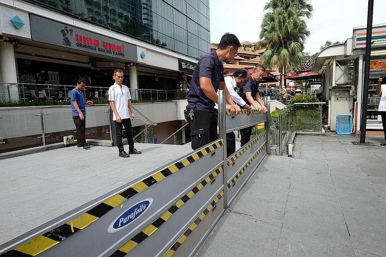 Workers from Forum The Shopping Mall in Orchard Road demonstrating how flood barriers are set up during the PUB briefing yesterday. They will be mobilised to set up the barricades should water activate flood sensors nearby.