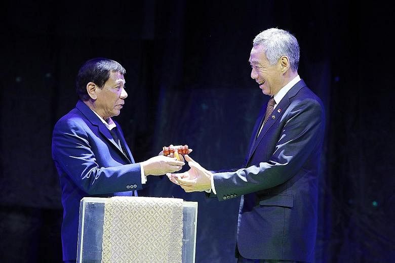 Philippine President Rodrigo Duterte giving Prime Minister Lee Hsien Loong a symbolic gavel to mark the handover of the rotating Asean chairmanship to Singapore at last night's closing ceremony for the 31st Asean Summit.